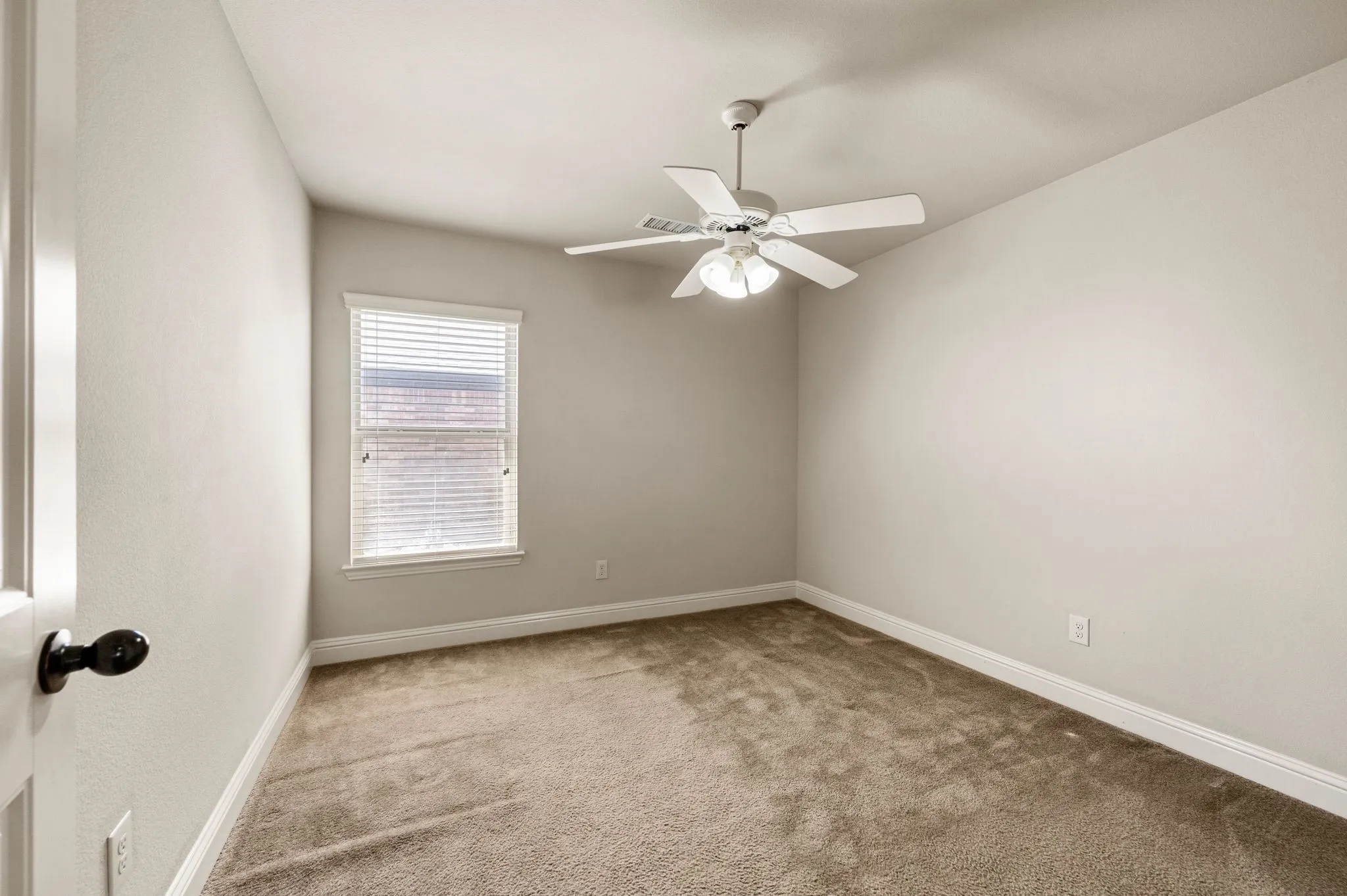 Neutral wall color, window with blinds, overhead ceiling fan, and carpeted flooring