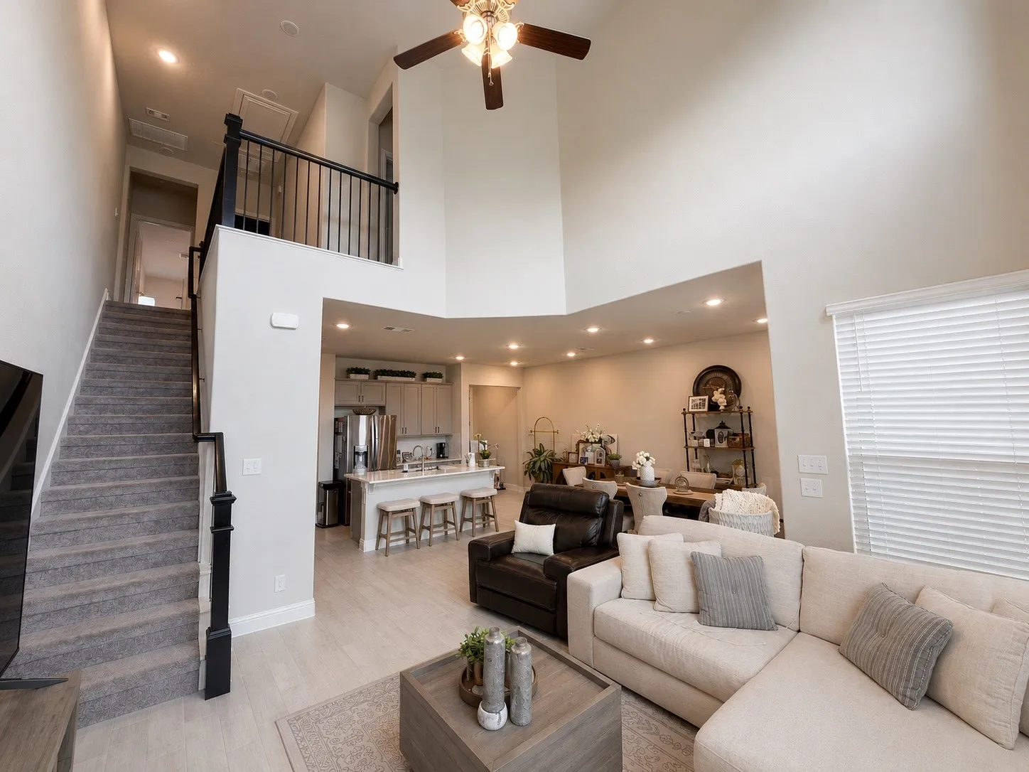 Open-concept living space featuring high ceilings, recessed lighting, wood-finish flooring, a ceiling fan, and a kitchen with stainless steel appliances
