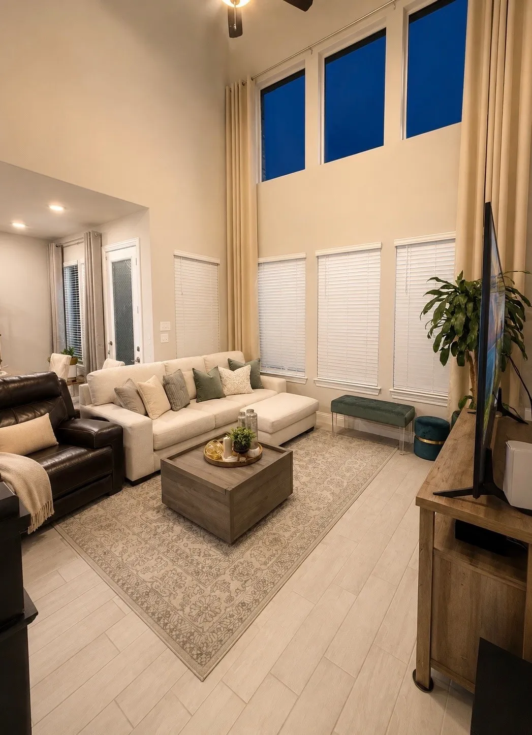 Soaring ceiling height, multiple windows with blinds, recessed lighting, ceiling fan, and light wood-finish flooring