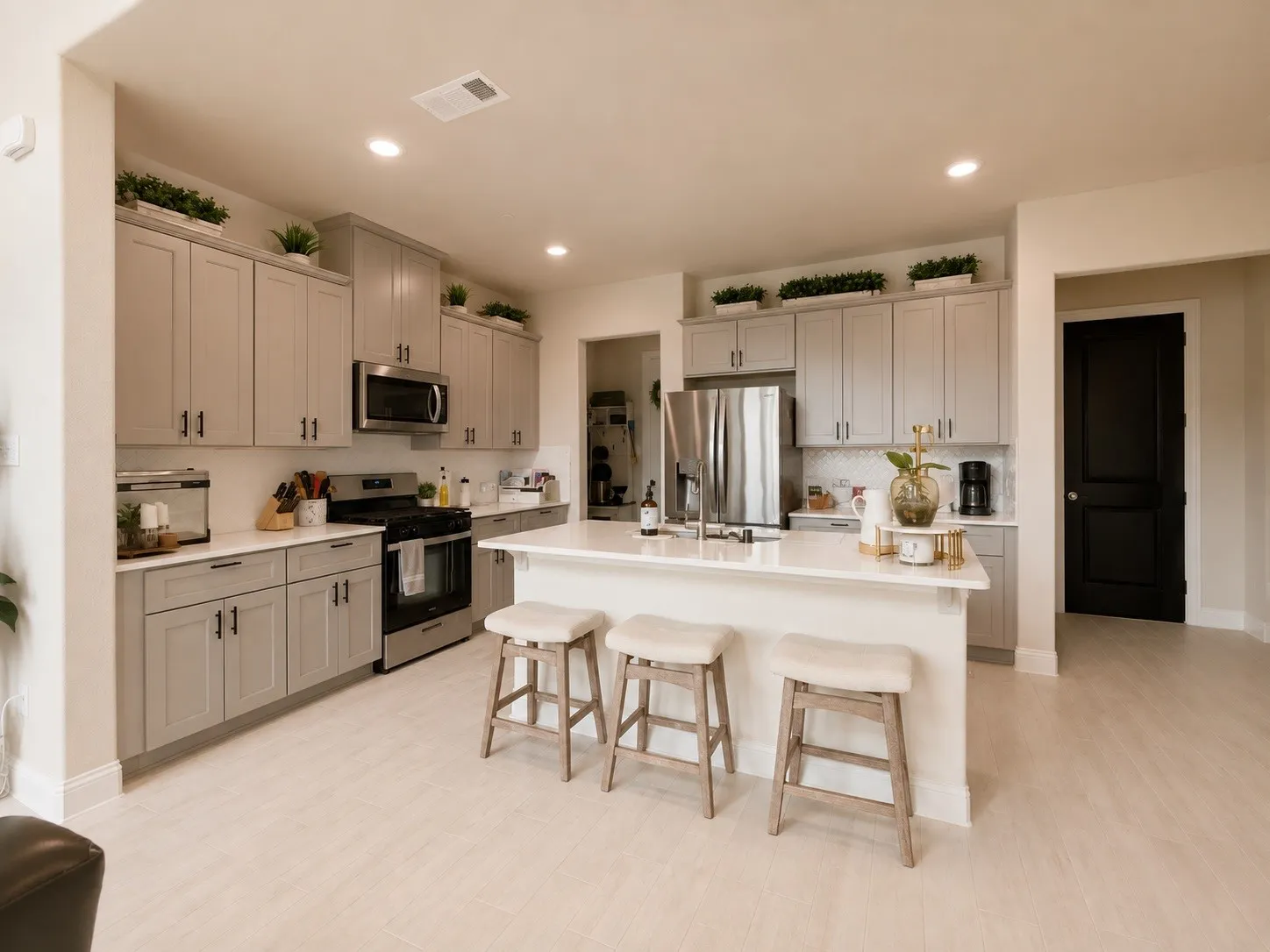 Kitchen featuring light wood-finish flooring, light gray cabinetry, stainless steel appliances, white countertops, and a central island with seating