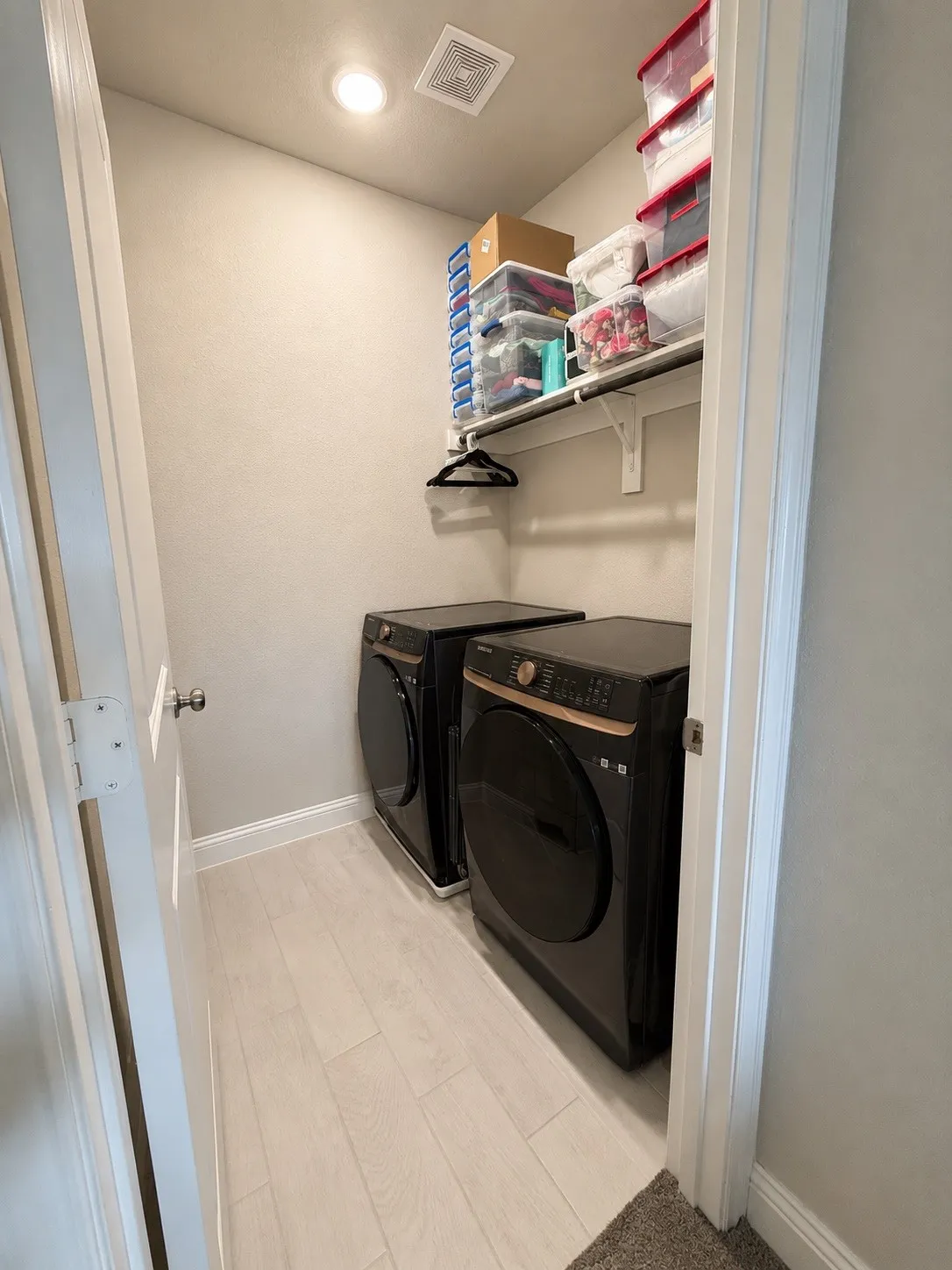 Light-toned wood-finish flooring, recessed ceiling lighting, and a wall-mounted shelf