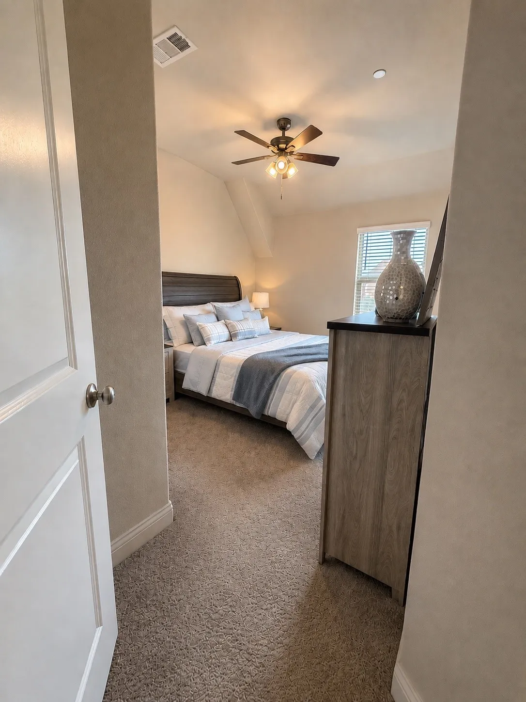 Carpeted flooring throughout, white interior door, and a ceiling fan with integrated lighting
