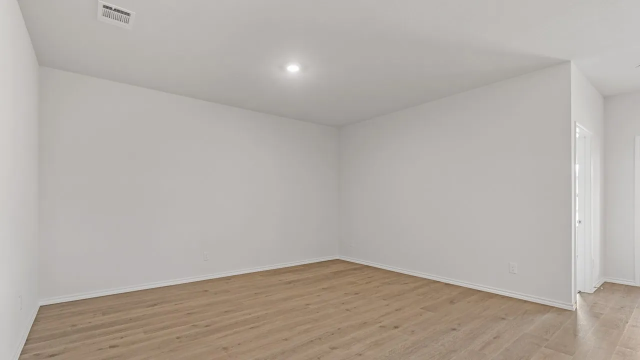 Spacious interior room with wood-finish flooring, white walls, and recessed lighting