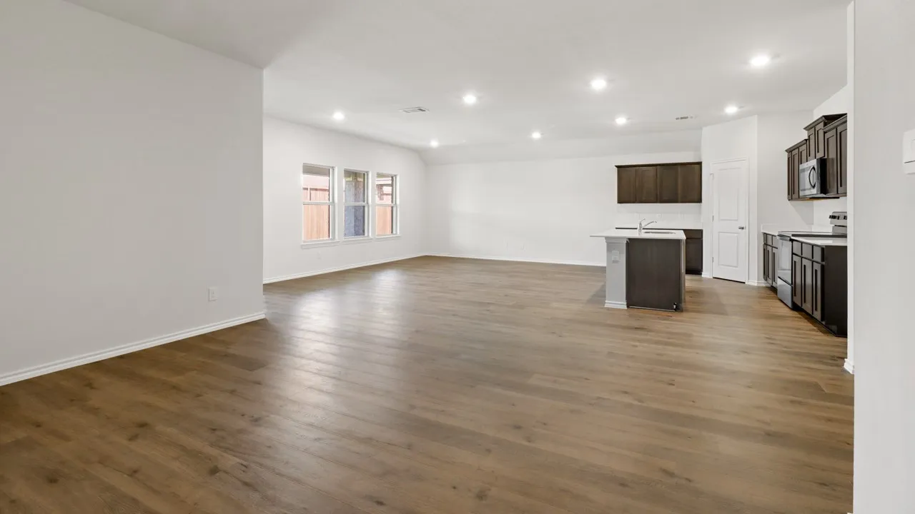 Expansive open-concept room featuring wood-finish flooring, recessed lighting, and a kitchen area