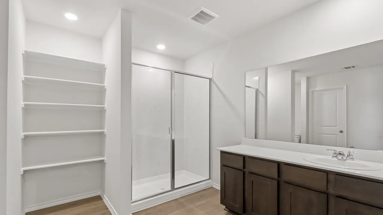 Contemporary bathroom featuring a spacious vanity with dark wood-finish cabinetry, a large integrated sink, and an expansive wall-mounted mirror