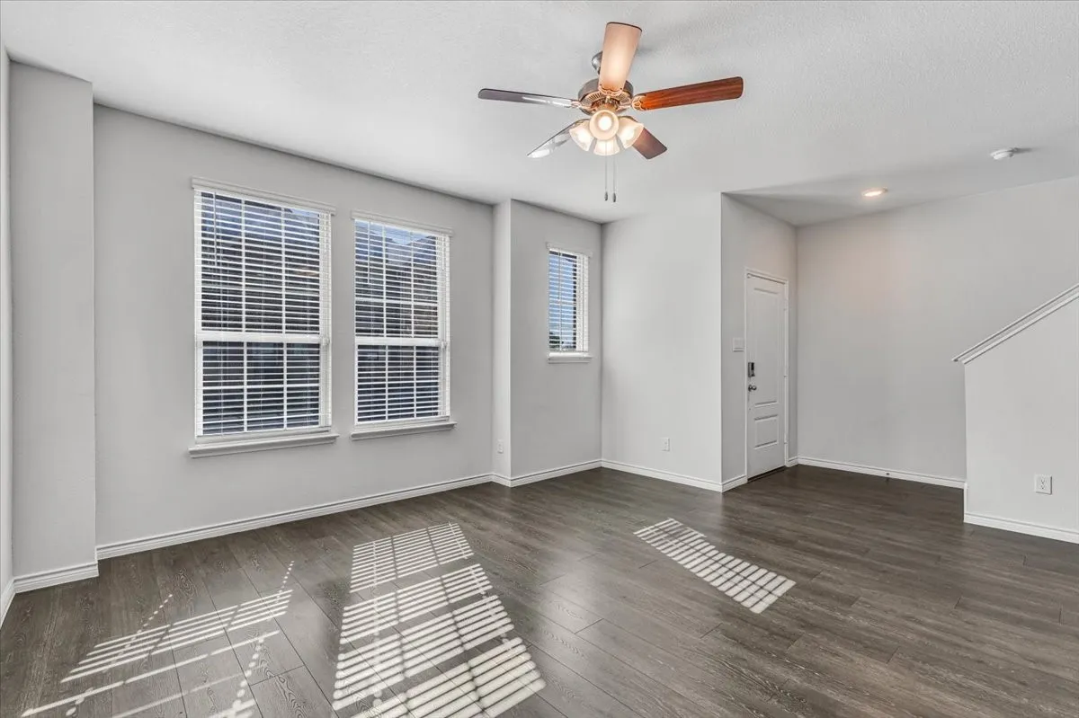 Spacious room featuring wood-finish flooring, multiple windows with blinds, a ceiling fan, and recessed lighting