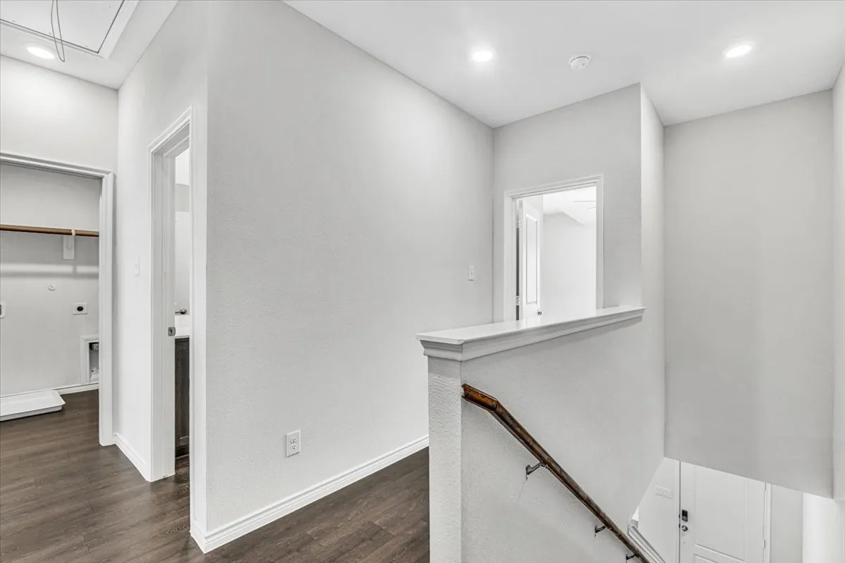 Hallway featuring wood-finish flooring, white walls, recessed lighting, and a built-in closet with shelving