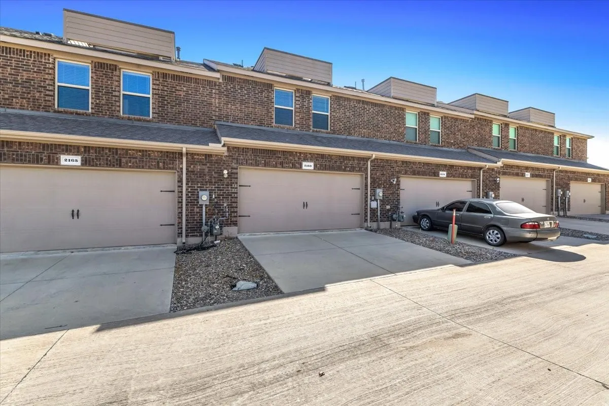 Brick exterior featuring multiple garages, individual driveways, and upper-level windows