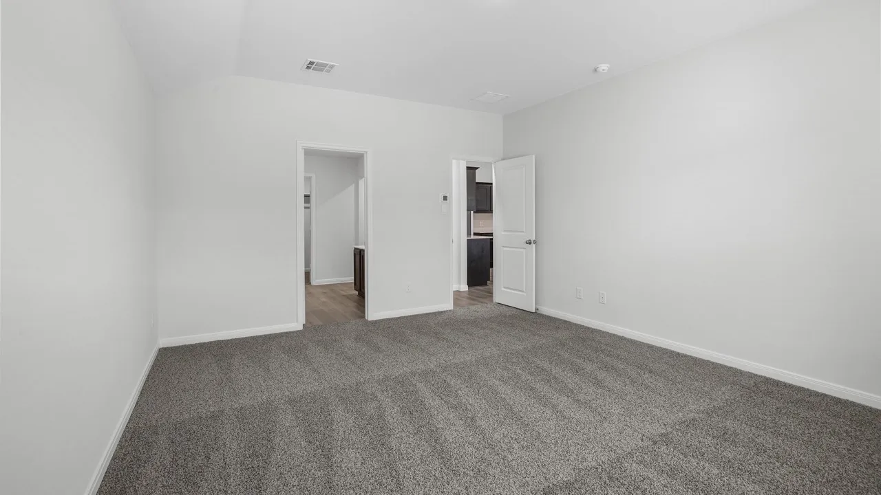 Spacious room featuring neutral carpeting, light-toned walls, and white trim