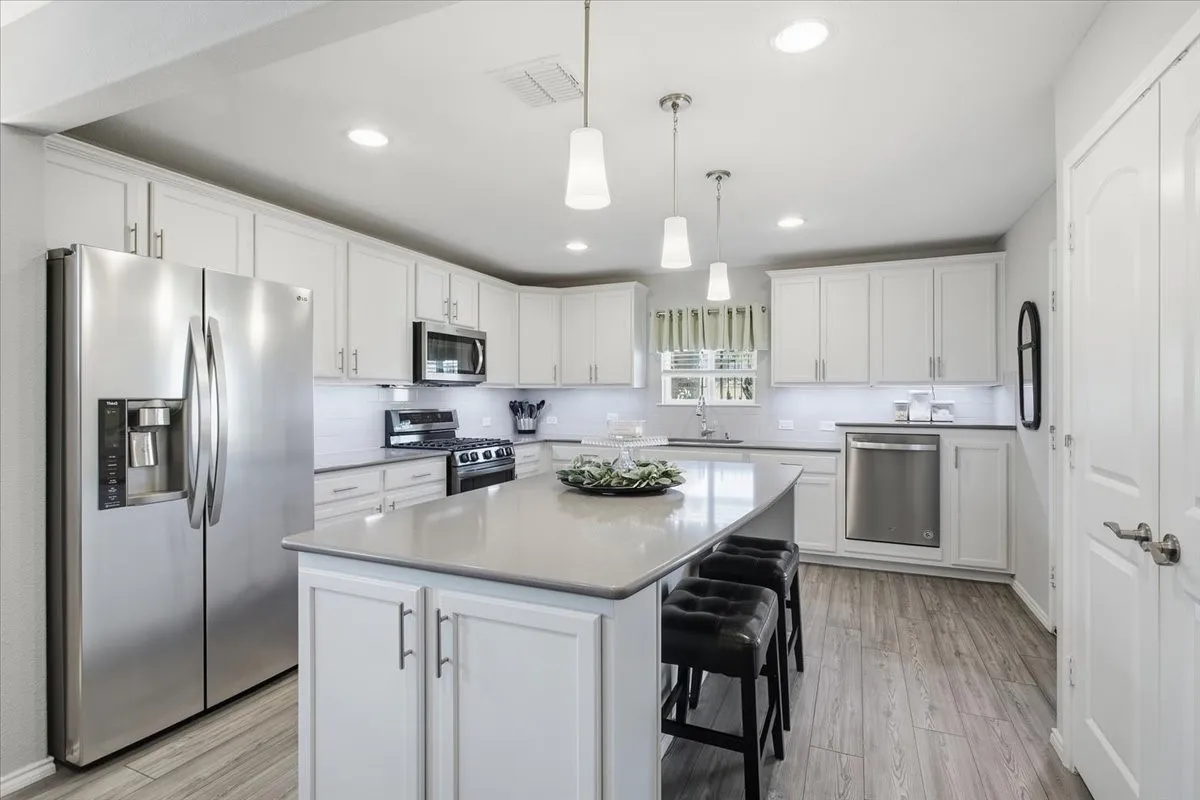 This kitchen is bright and open with quartz countertops and under cabinet lighting.