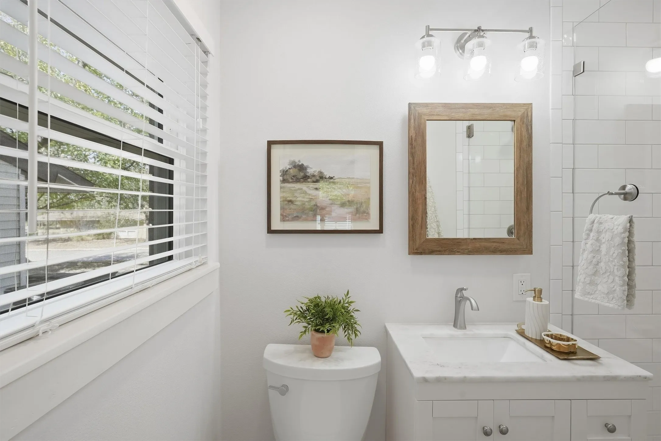 This primary bathroom features a window great for adding natural light that fills the space, and an enclosed shower with clean