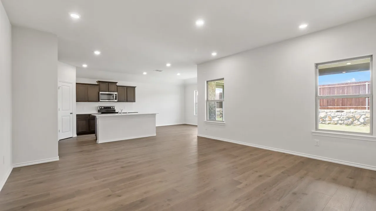 Spacious open-concept interior featuring wood-finish flooring, recessed lighting, and a modern kitchen island with an undermount sink