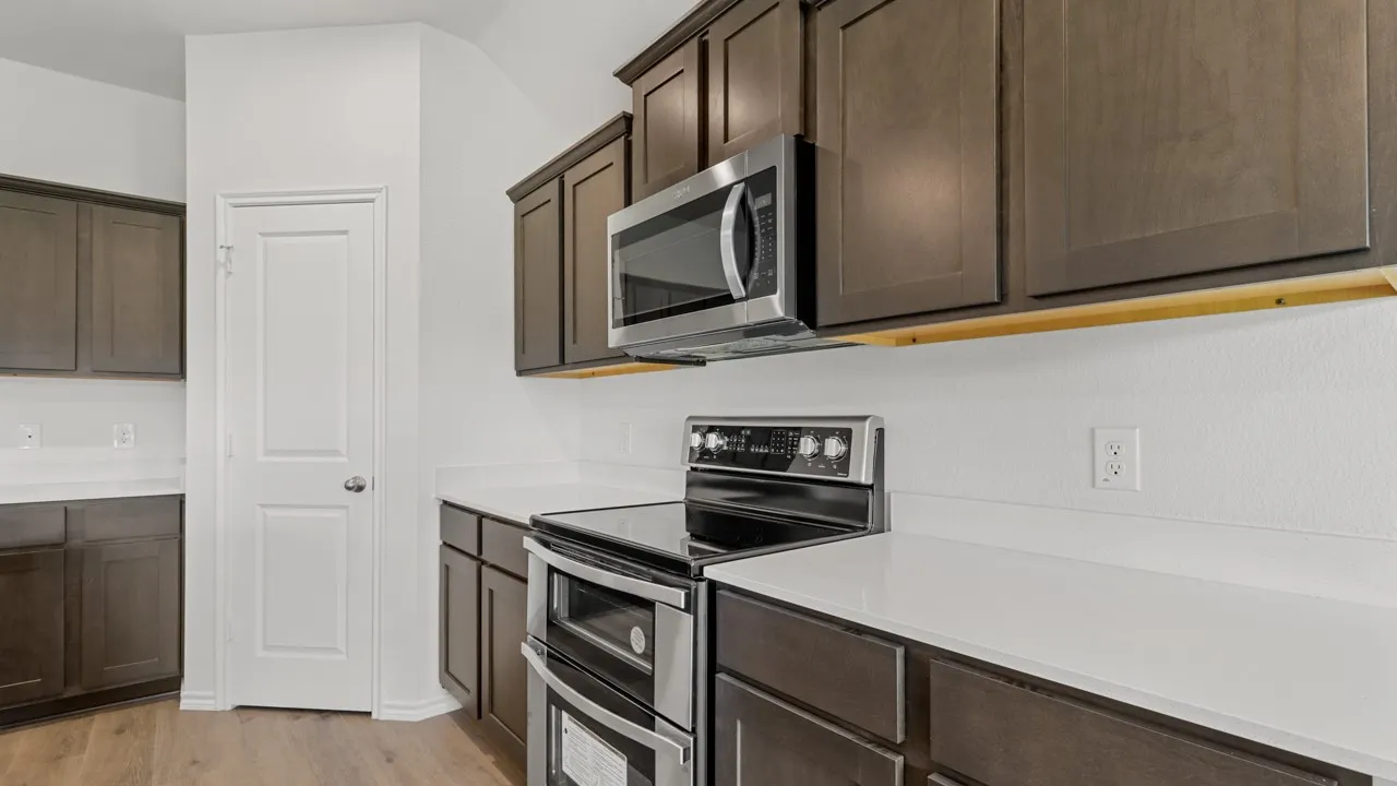 Modern kitchen with stainless steel appliances, dark wood-finish cabinetry, and light-toned countertops