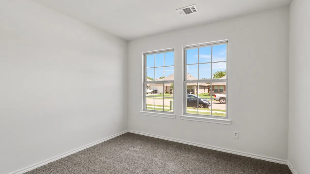 Room featuring two multi-pane windows, neutral wall tones, white baseboards, and grey carpeting