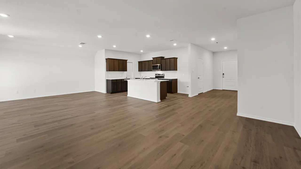 Open-concept living area featuring wood-finish flooring, recessed lighting, and a kitchen with white countertops, dark wood cabinetry, and stainless steel appliances