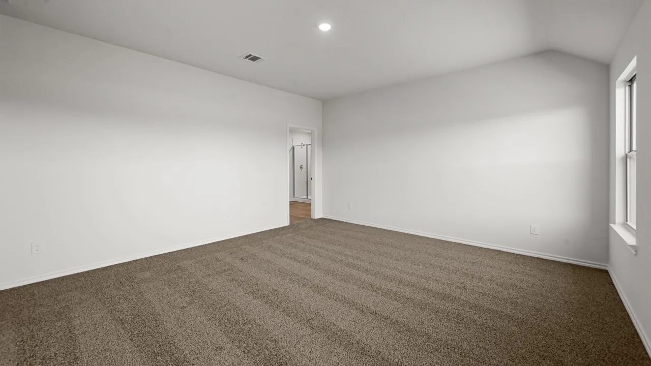Spacious room featuring vaulted ceilings, neutral-toned carpet, recessed lighting, and a double-paned window