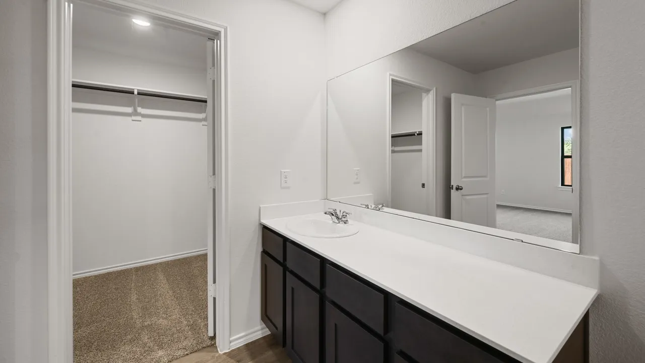 Bathroom vanity with an integrated sink, polished chrome faucet, and a wall-mounted mirror