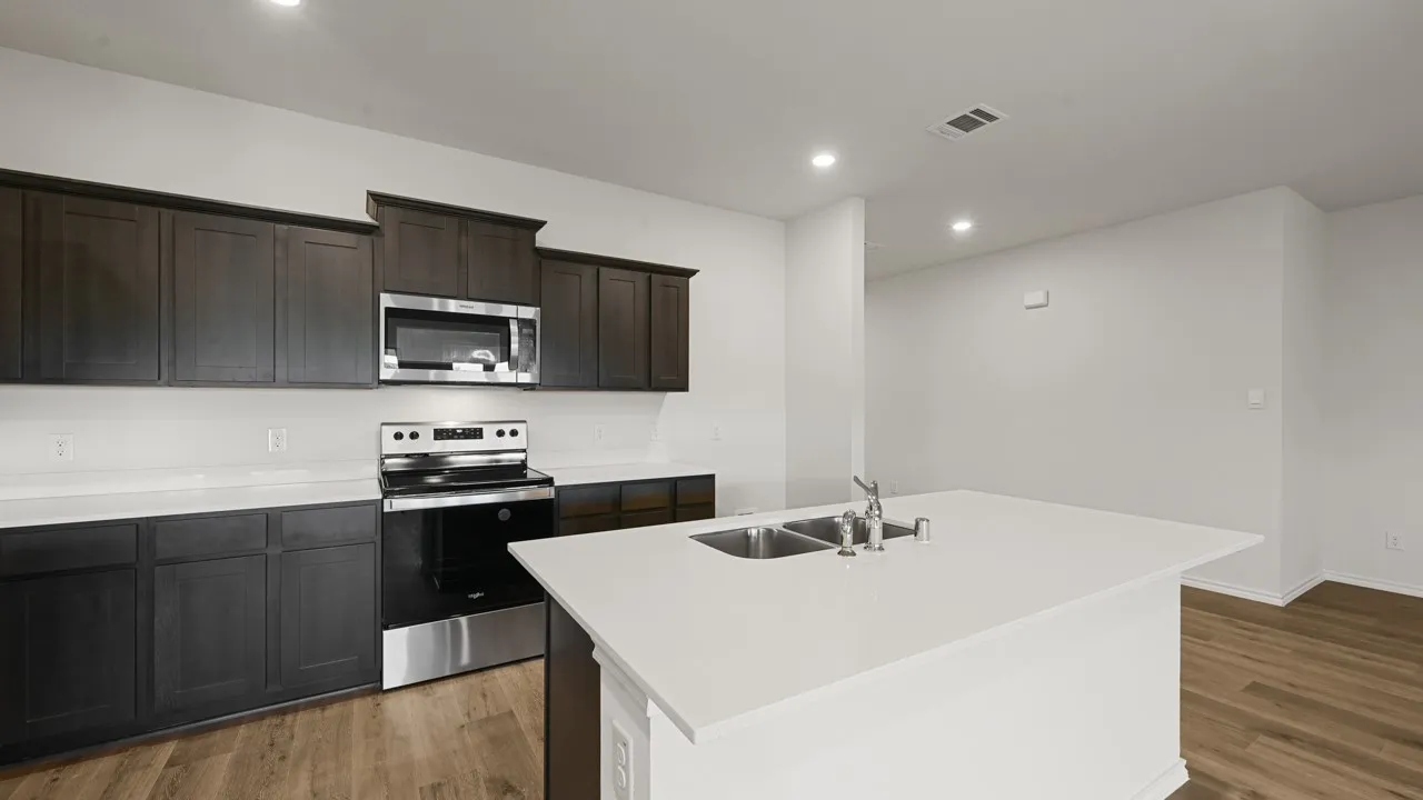 Modern kitchen with dark wood-finish cabinetry, light-toned countertops, and stainless steel appliances