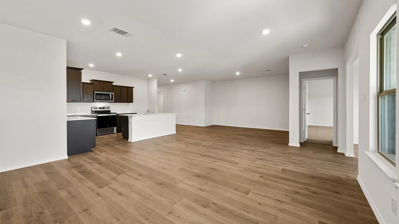Open-concept living area featuring wood-finish flooring, recessed lighting, and a neutral color palette