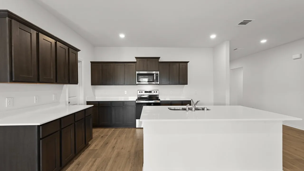 Contemporary kitchen featuring dark wood cabinetry, white countertops, a stainless steel microwave, and wood-finish flooring