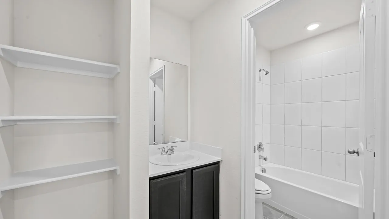 Bathroom featuring a dark vanity with a white countertop, an integrated sink, and a framed mirror