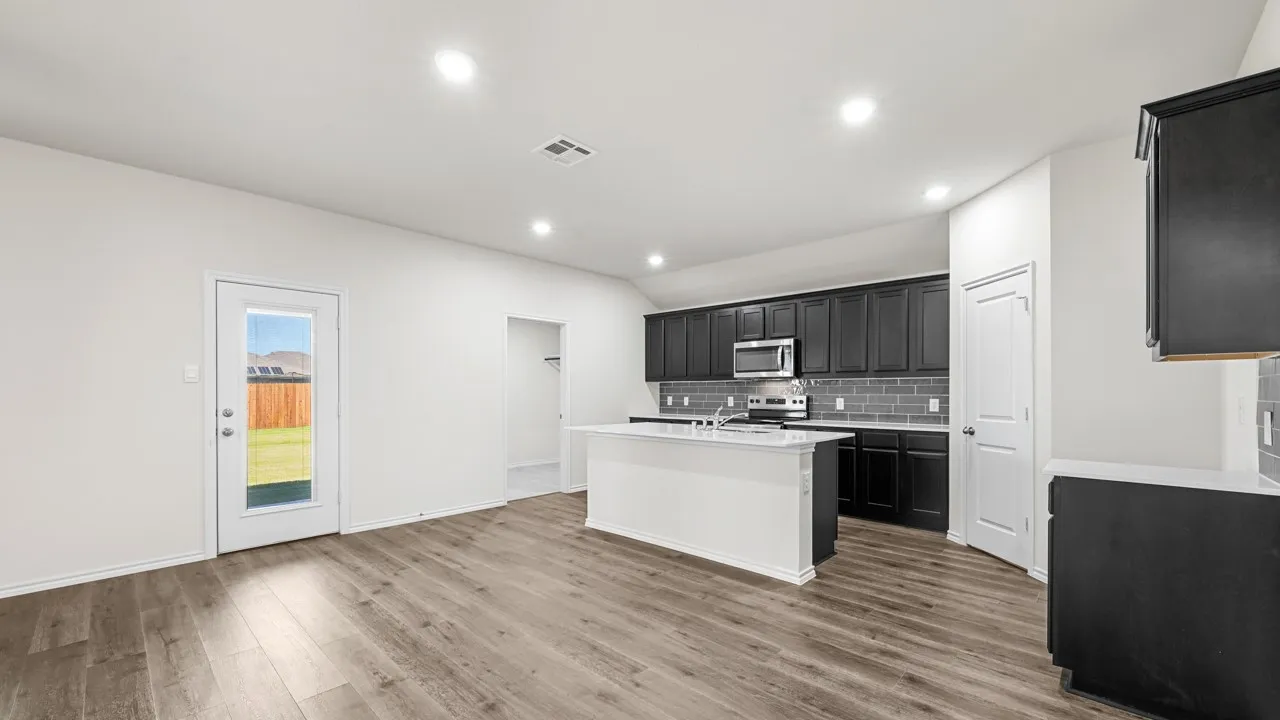 Open-concept living space featuring wood-finish flooring, recessed lighting, and a modern kitchen with dark cabinetry