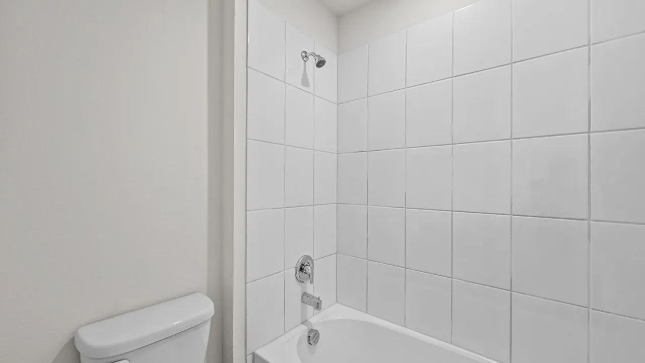 Bathtub with white subway tile surround, chrome fixtures, and a showerhead