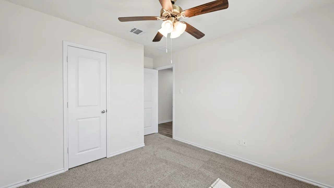 Neutral-toned wall finishes with a ceiling fan, white trim work, and light-colored carpeting