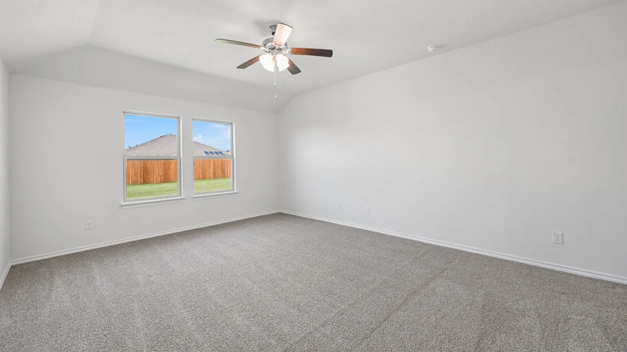 Expansive room featuring vaulted ceilings, a ceiling fan, dual windows, and plush grey carpeting