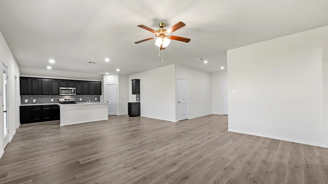 Expansive open-concept living area featuring wood-finish flooring, recessed lighting, and a ceiling fan