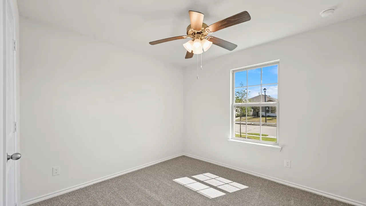 Bright room featuring neutral walls, gray carpeting, a ceiling fan with integrated lighting, and a single window