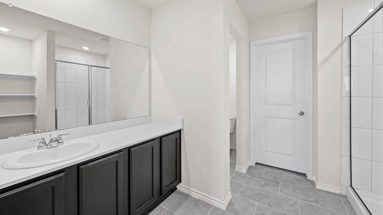 Bathroom vanity featuring a single basin, dark cabinetry, and an expansive mirror