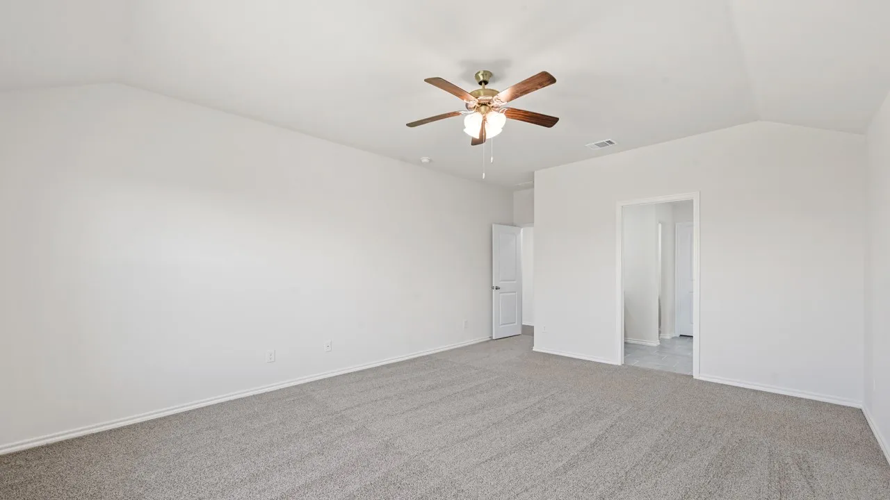 Spacious room featuring vaulted ceilings, light gray carpeting, and a ceiling fan with integrated lighting