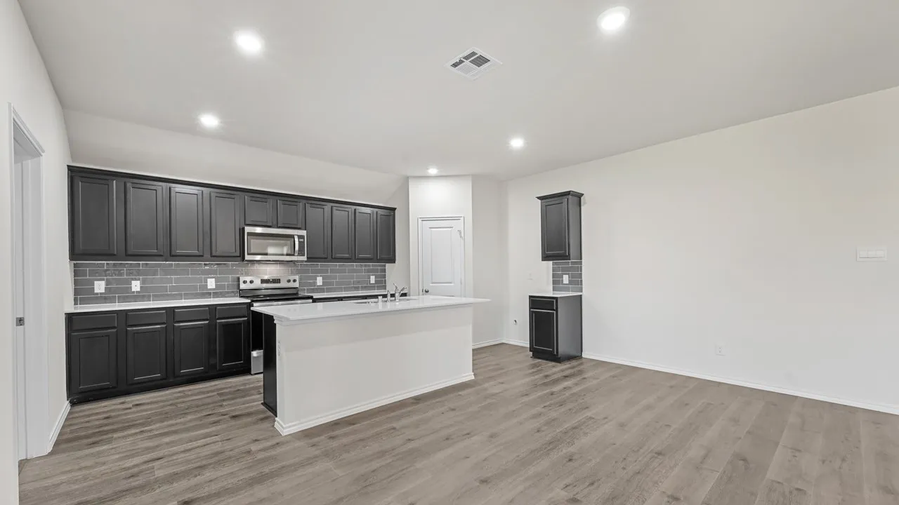 Modern kitchen featuring dark cabinetry, stainless steel appliances, a subway tile backsplash, and a central island with a sink
