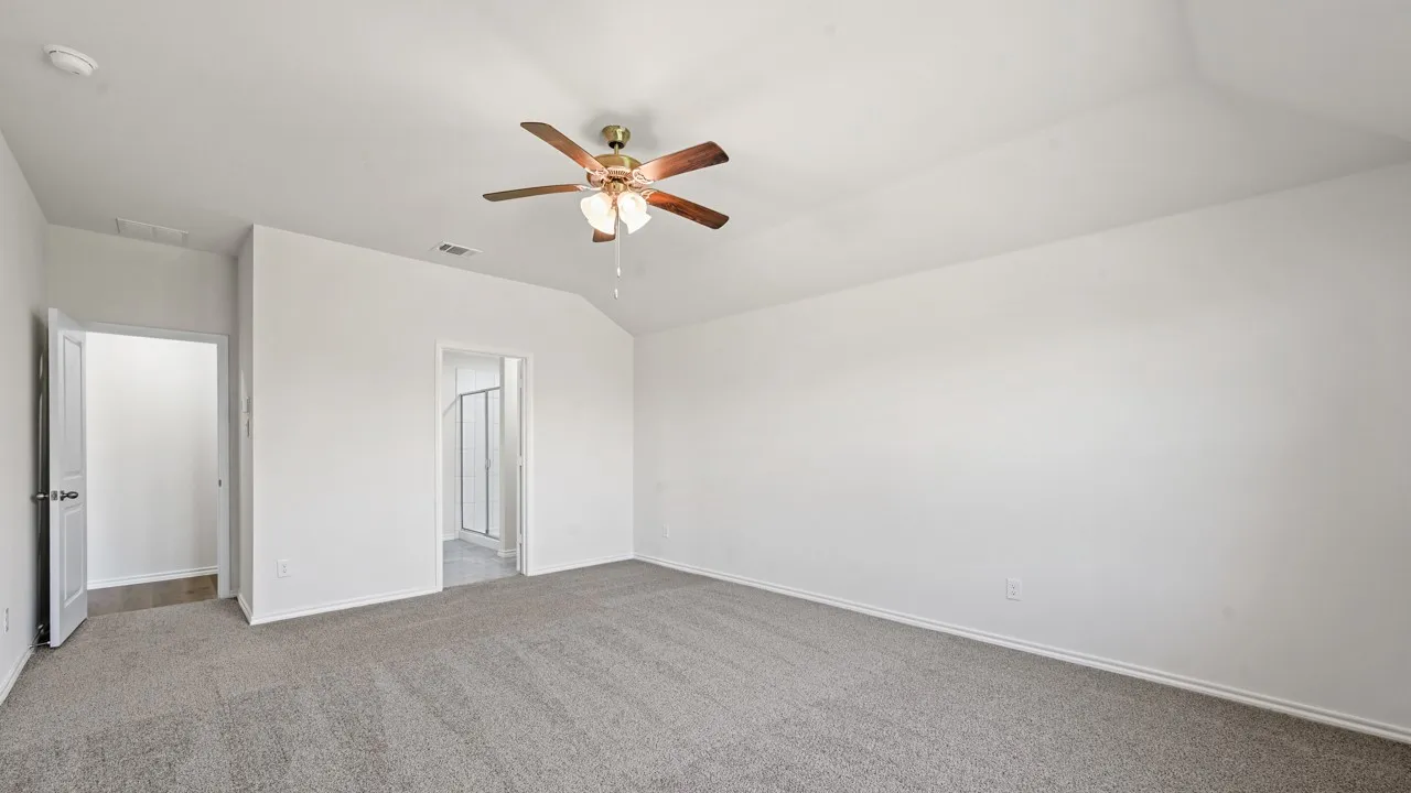Carpeted room featuring a ceiling fan with light fixture, vaulted ceiling, white walls, and white trim
