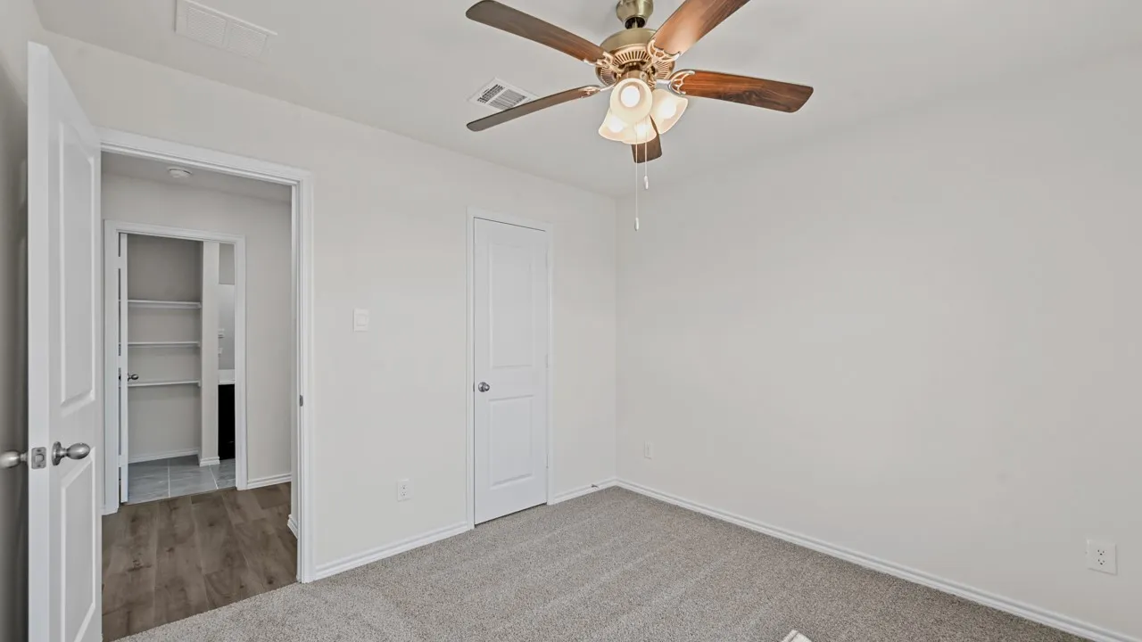 Carpeted room with a ceiling fan light fixture
