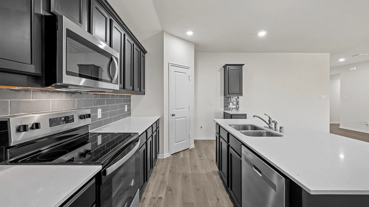 Modern kitchen featuring dark cabinetry, white countertops, stainless steel appliances, a subway tile backsplash, and wood-finish flooring