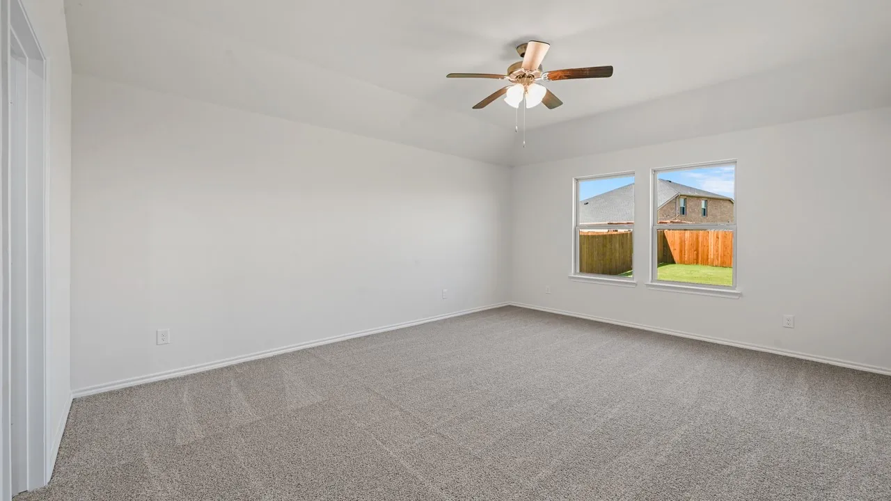 Spacious interior room featuring light gray carpet flooring, white walls, two windows, and a ceiling fan with light fixture