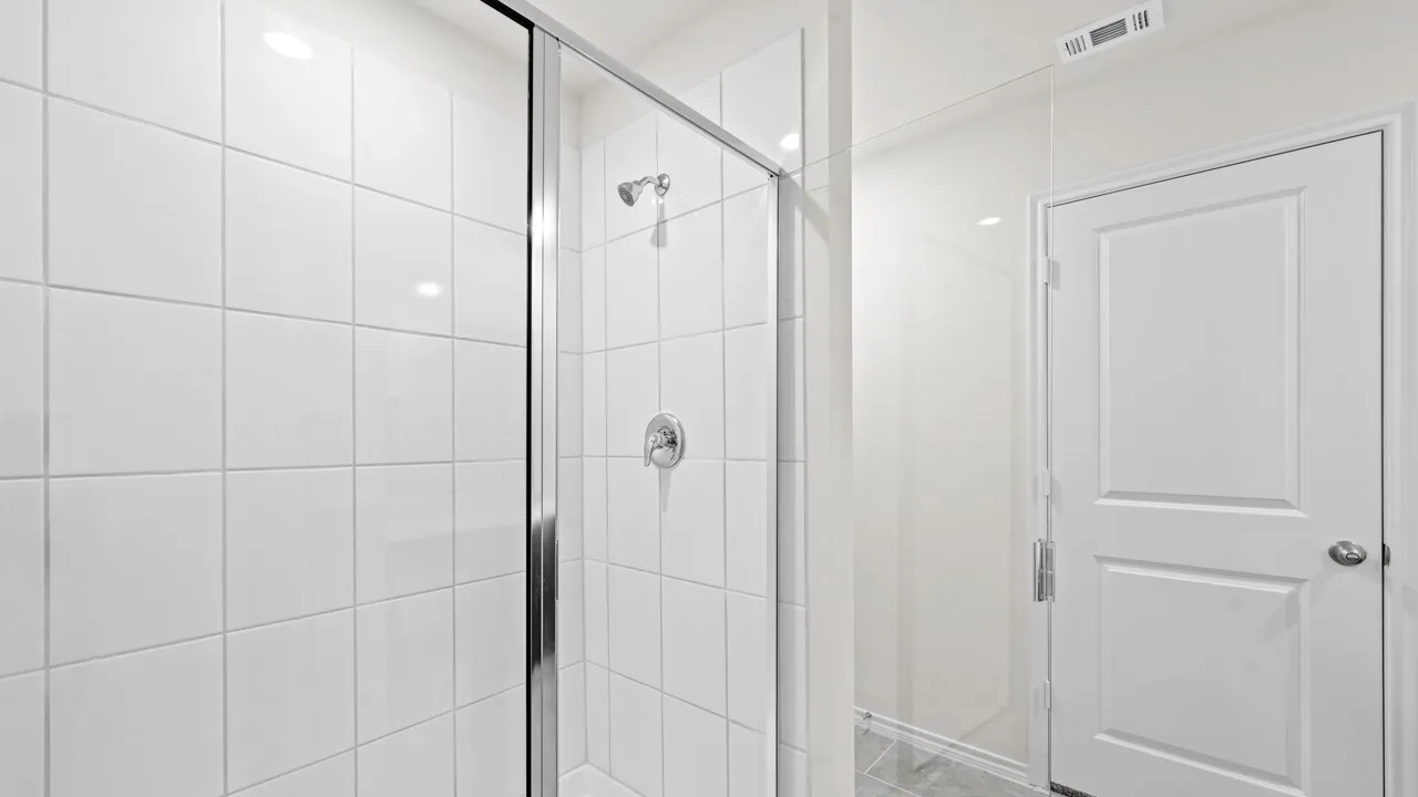Spacious walk-in shower featuring white square tile surround, clear glass enclosure, and chrome fixtures