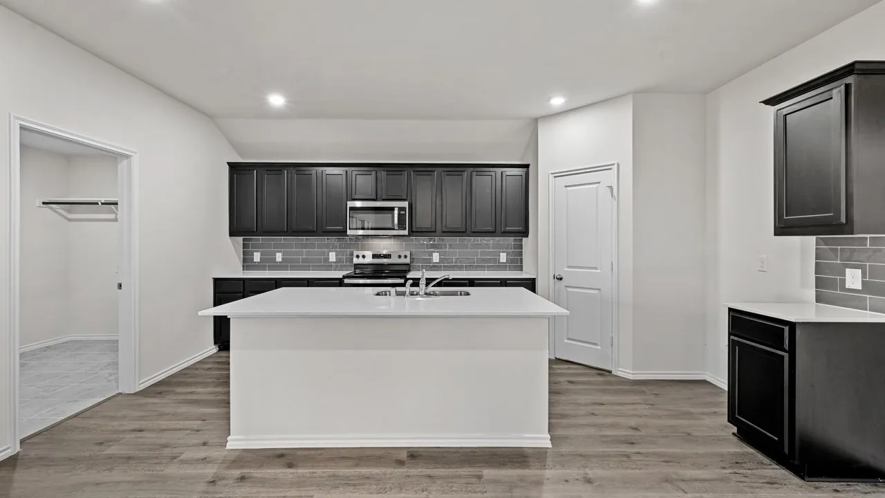 Kitchen featuring a center island, dark wood-finish cabinetry, stainless steel appliances, a subway tile backsplash, and wood-finish flooring