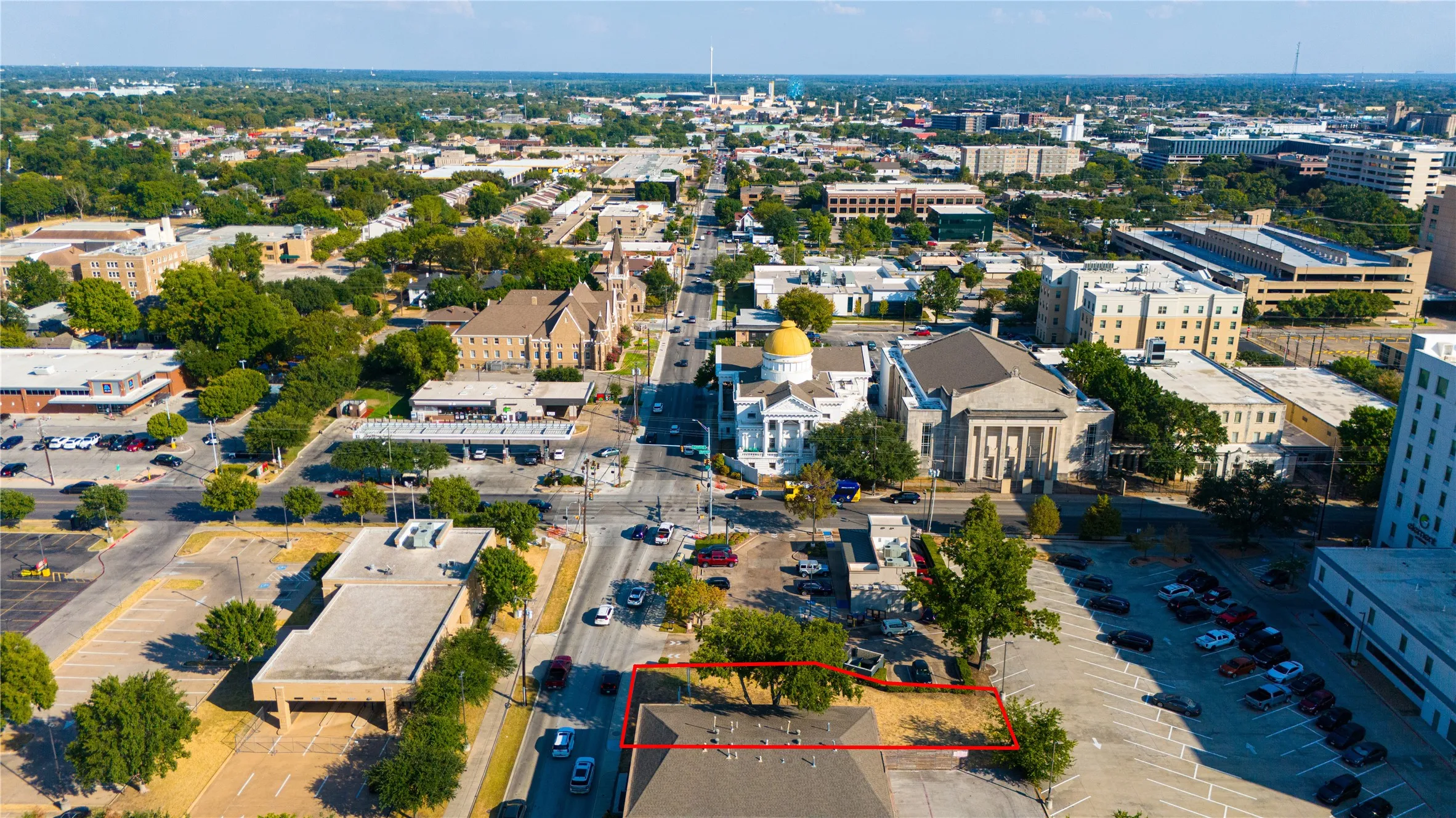 Cleared lot with direct street access, mature trees, and a surrounding urban landscape