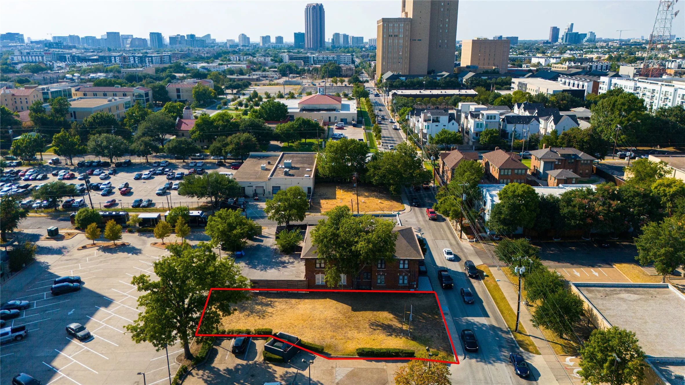Cleared lot with direct street access, mature trees, and a surrounding urban landscape