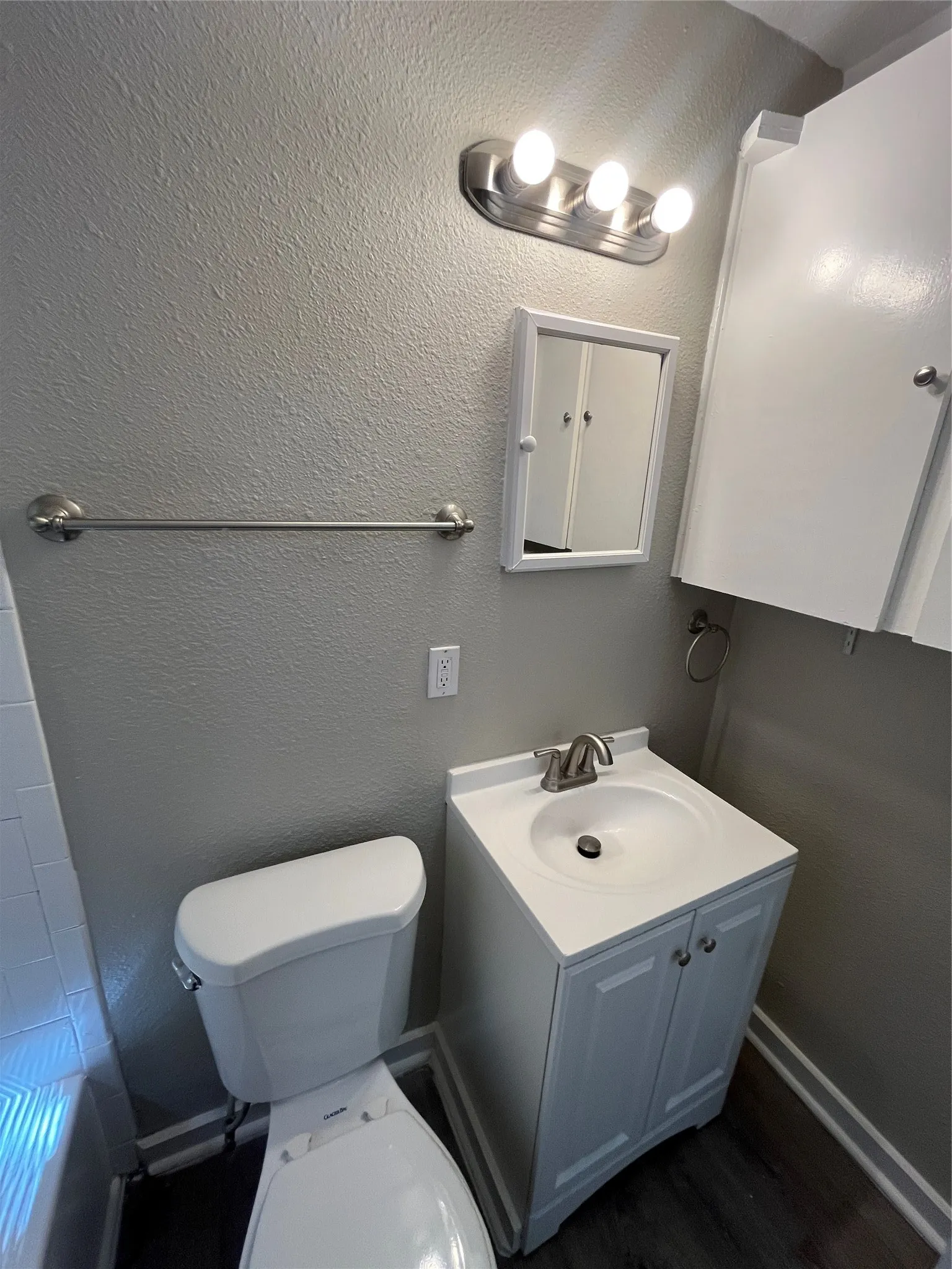 Modern vanity with integrated sink, brushed nickel faucet, wall-mounted medicine cabinet, and overhead light fixture