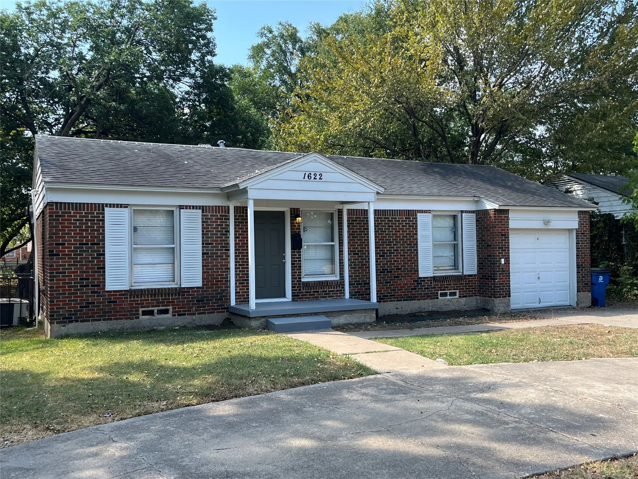 Brick exterior featuring white shutters and a covered entry