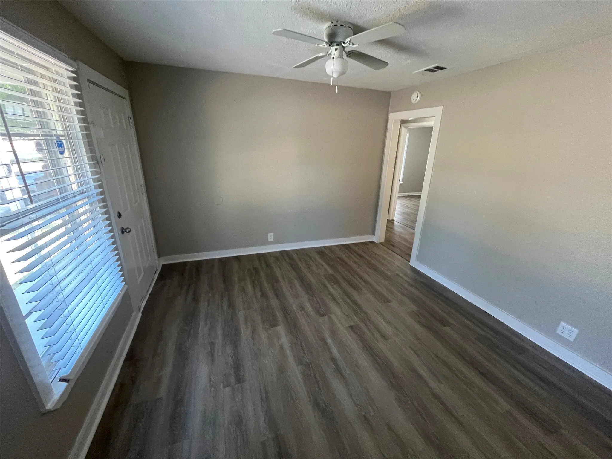 Wood-finish flooring, ceiling fan with integrated lighting, neutral wall paint, and white trim