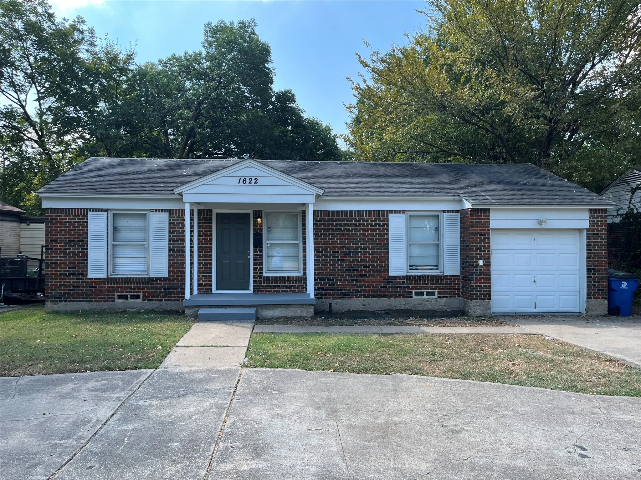 Brick exterior featuring white shutters and a covered entry