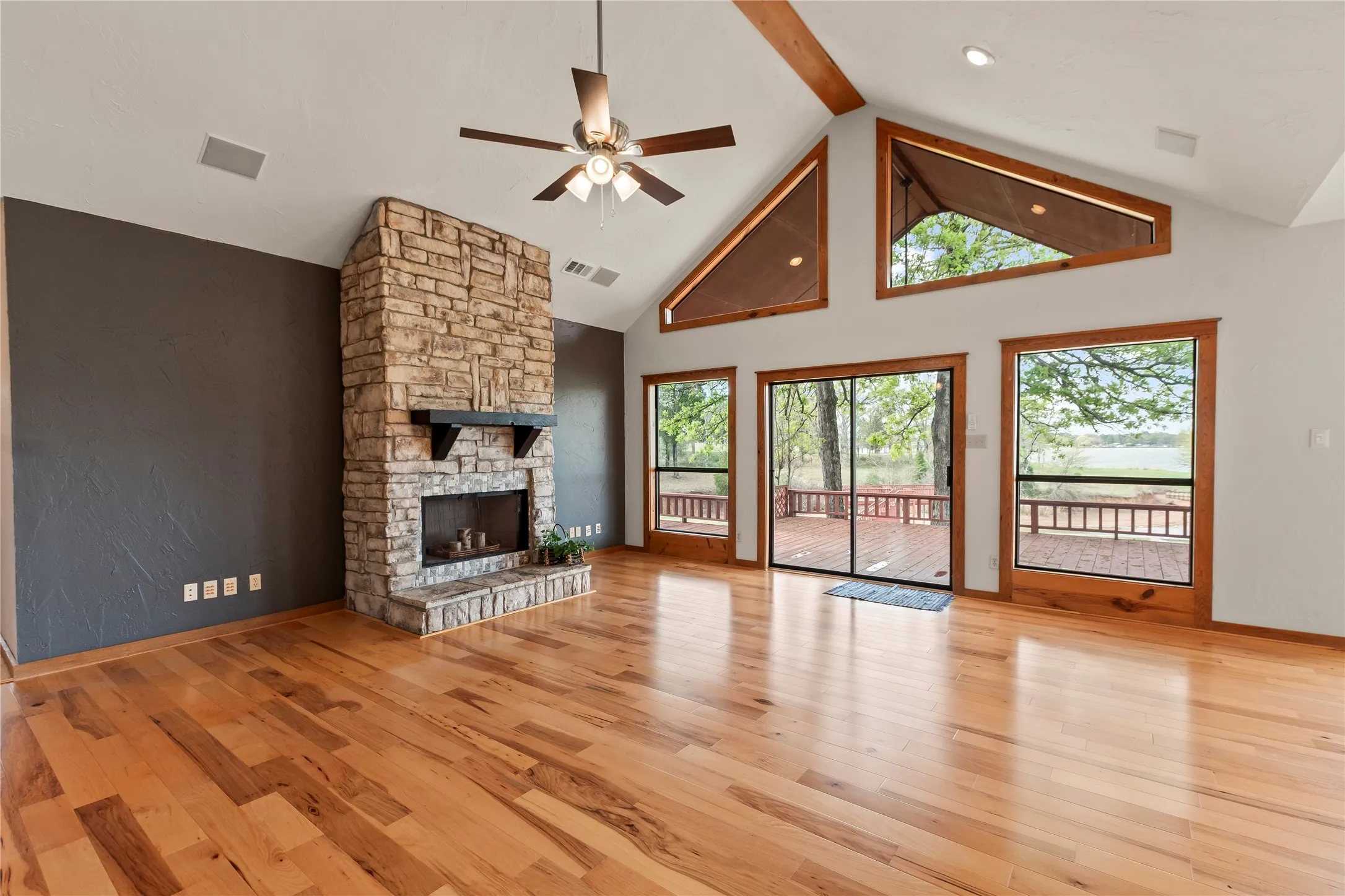 Open living area with vaulted ceilings and stone fireplace. Beautiful Bellawood Engineered Hickory flooring.