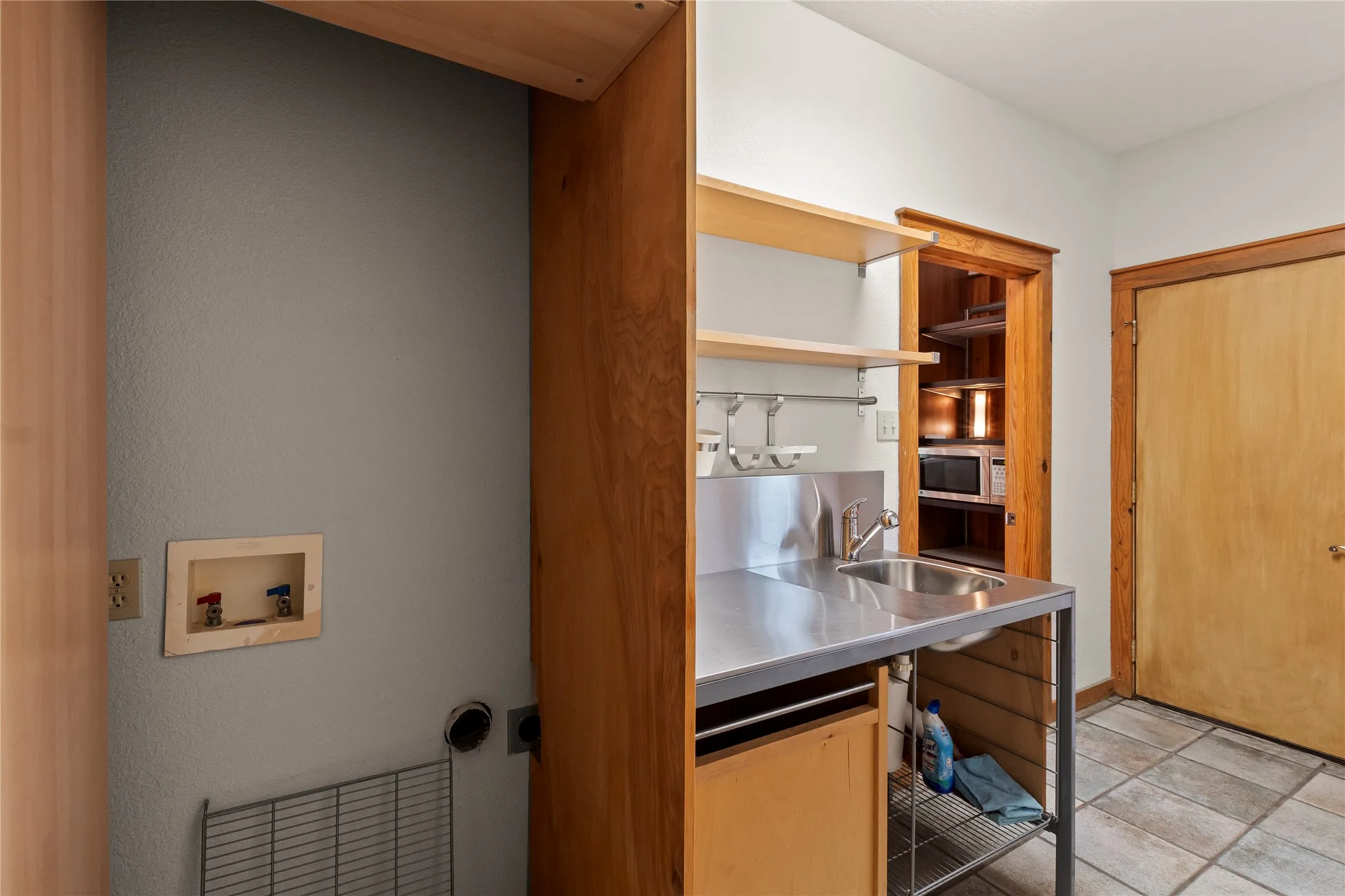 Space for a standard size stackable washer and dryer. The wood door to the right of the image is an exit to the exterior of the home.