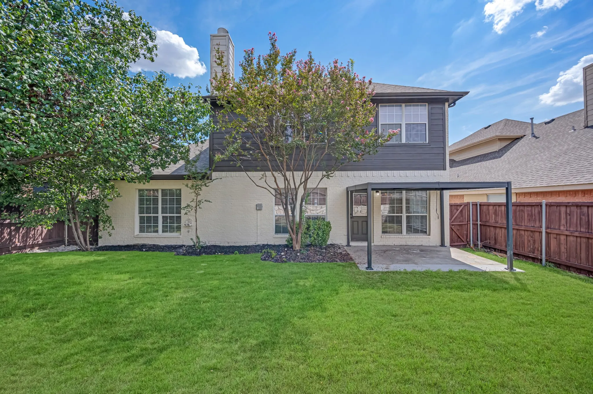 Expansive lawn, covered patio, wood privacy fencing, and mature trees complement the exterior
