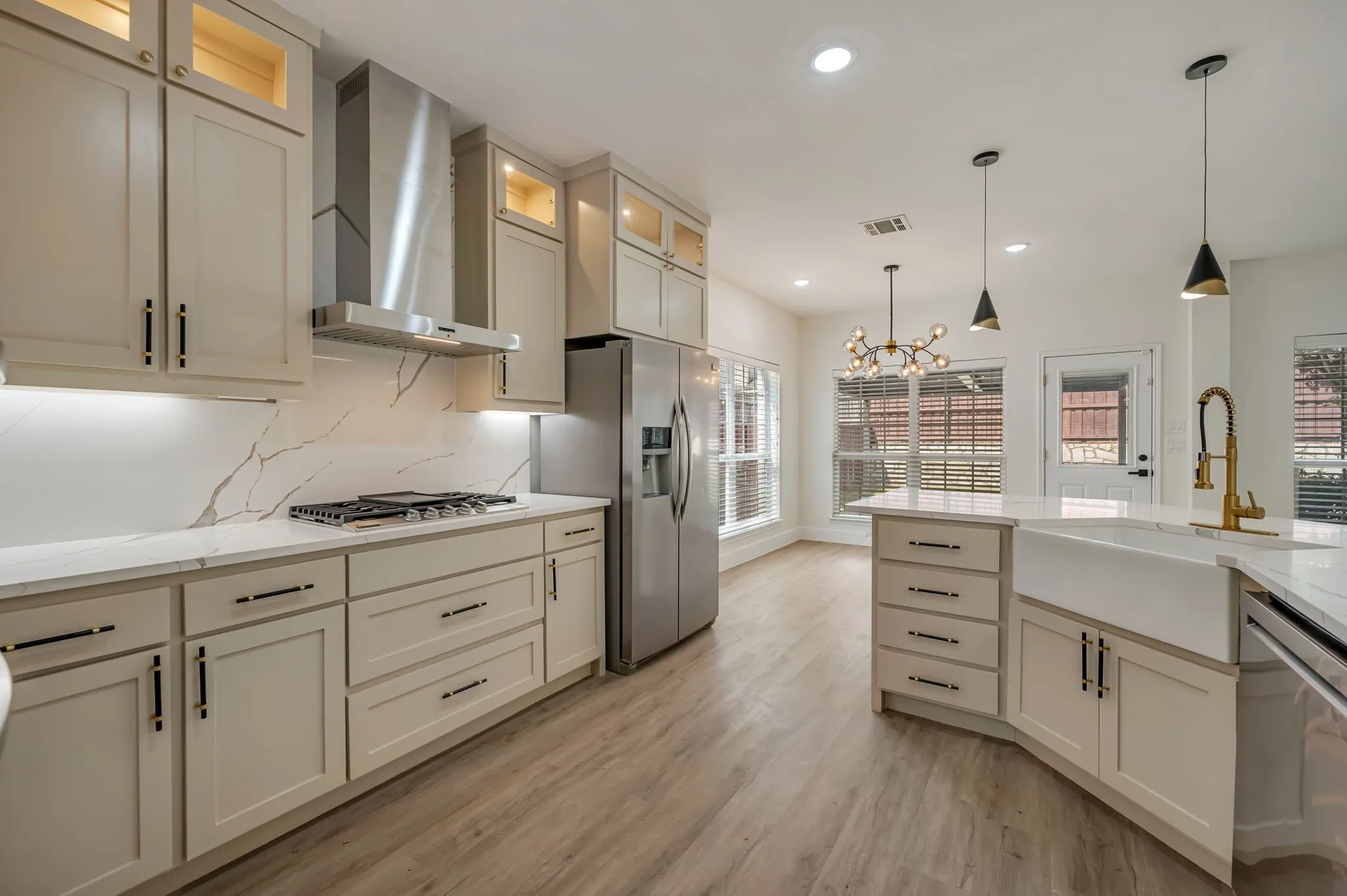 Modern kitchen featuring light-toned cabinetry, stainless steel appliances, a farmhouse sink, and Luxury Vinyl Plank  flooring